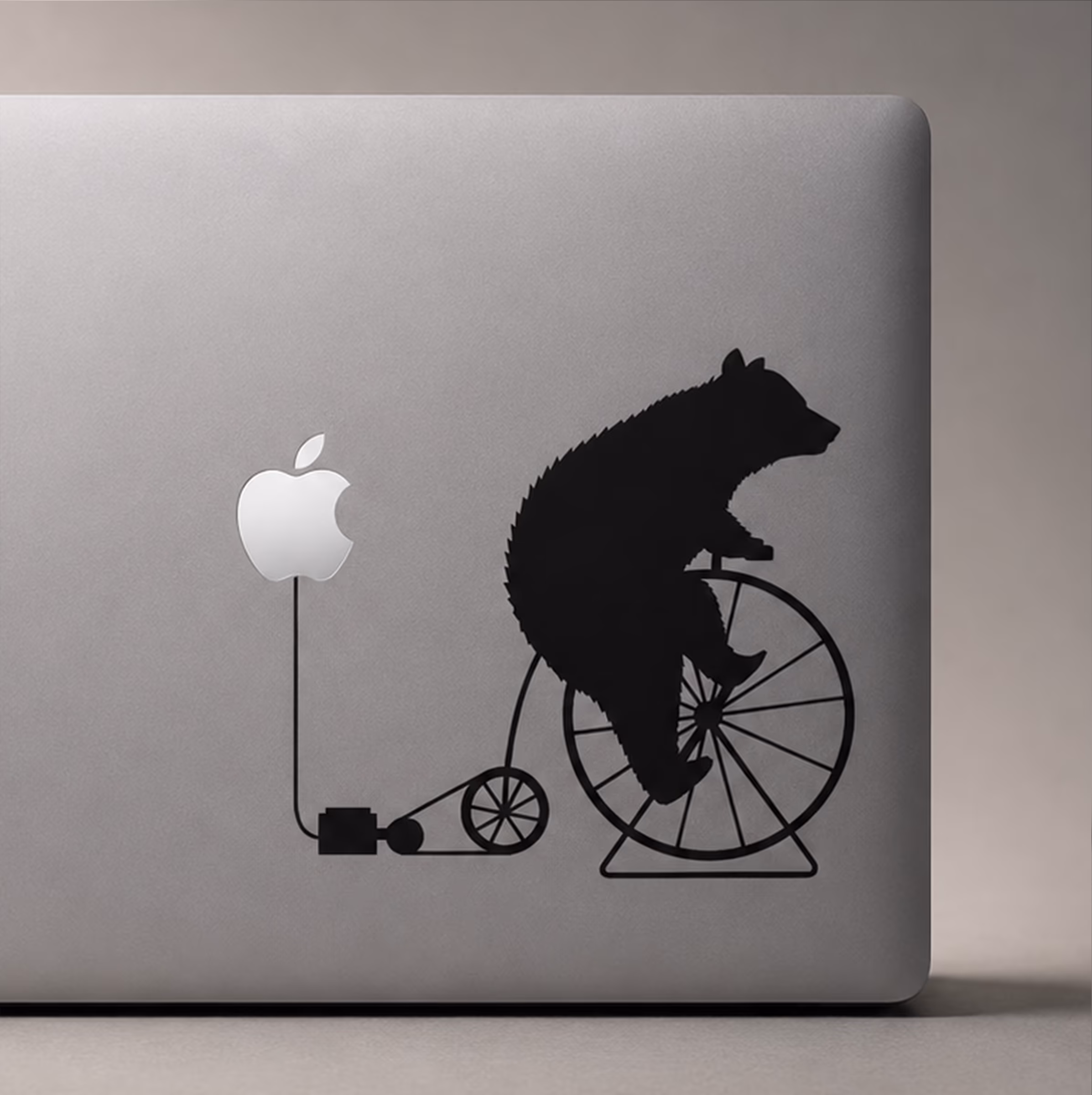 MacBook decal of a bear riding a penny-farthing powered by the Apple logo